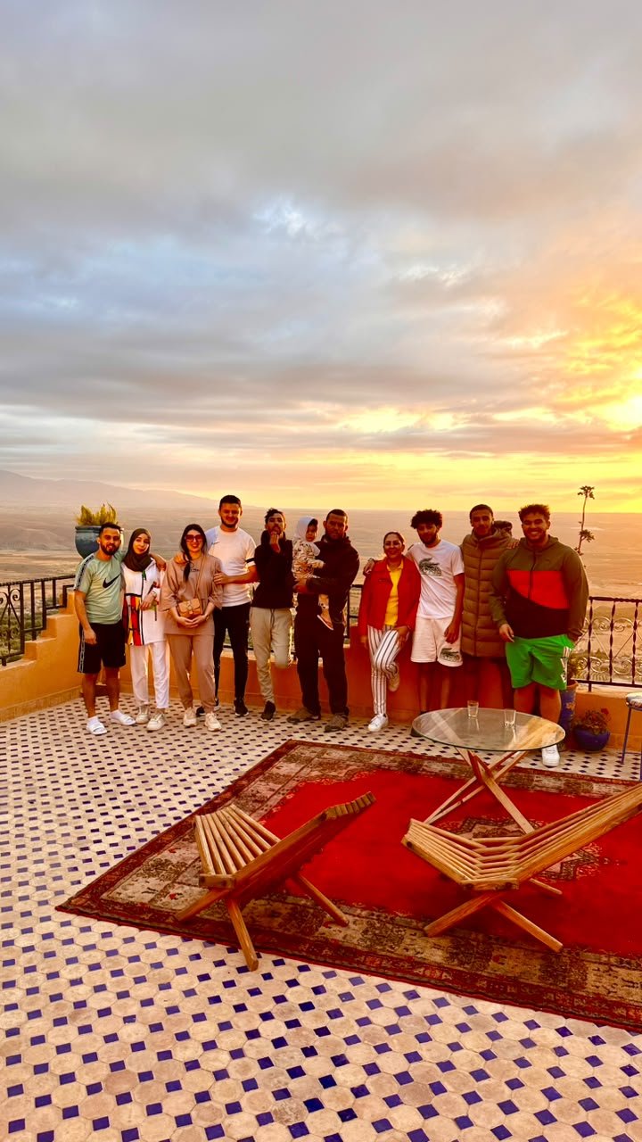 Groupe sur une terrasse en zellige au coucher du soleil face à l'Atlas, près de Marrakech